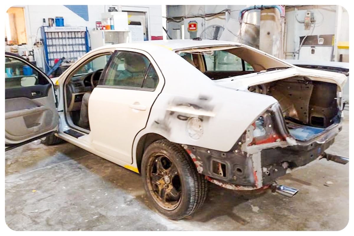 White Ford Fusion in the shop during collision repair